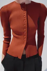 Chaqueta de punto color óxido, con cuello redondo, manga larga abullonada y cierre frontal con botones.