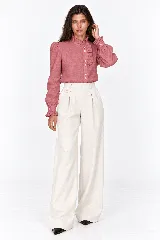 Blusa rosada de 100% lino natural, con cuello alto con volado, mangas largas abullonadas y cierre frontal de botones con detalles de volados en la cartera.