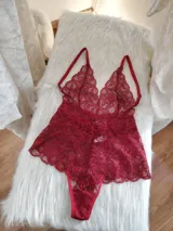 Body de encaje color rojo con escote pronunciado, breteles regulables y diseño tipo tanga en la parte inferior.