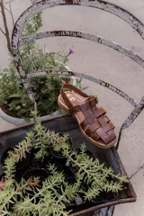 Sandalias de cuero con tiras entrecruzadas, suela plana y hebilla lateral.