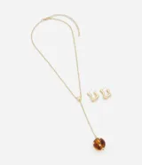 Conjunto de collar y caravanas dorados. El collar es tipo gravata con una cadena fina y un colgante de esfera roja. Los aros son aros pequeños con forma orgánica.