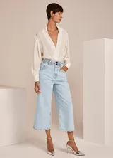 Body color crudo con cuello solapa, escote en V, manga larga con botones en los puños y detalles fruncidos.