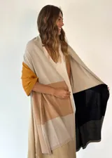 Pashmina de tejido de punto fino con diseño de bloques de color en tonos beige, mostaza, negro y marrón claro.