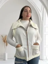 Chaleco blanco con cierre frontal, cuello y bolsillos con textura de piel sintética.