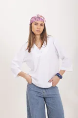 Blusa blanca de lino y viscosa, de corte holgado, con mangas tres cuartos y cuello en V decorado con volados.