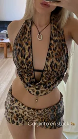 Conjunto de dos piezas compuesto por un top halter con escote profundo y una falda corta, ambos confeccionados en tela con estampado animal print de leopardo y recubiertos de lentejuelas brillantes.