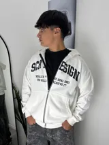 Campera con capucha y cierre frontal, color blanco, con estampado gráfico en negro en el pecho. Presenta bolsillos tipo canguro y puños elásticos.
