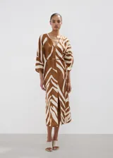 Vestido midi con estampado animal print tipo cebra en tonos marrón y blanco, de corte recto, con escote en V, mangas tres cuartos y tajo delantero en la falda. Incluye un cinturón fino ajustable.