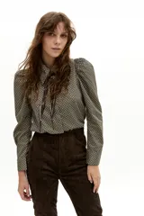 Camisa de manga larga confeccionada en popelina de algodón, con estampado geométrico en tonos verdes y negros. Presenta cuello clásico camisero, hombros ligeramente abullonados y cierre frontal con botones de nácar.
