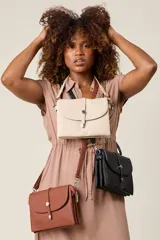 Bandolera negra de ecocuero con correa ajustable y solapa con cierre de botón metálico.