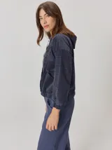 Campera estilo hoodie semi aterciopelada de color azul marino con sutil estampa de cuadros, mangas largas, capucha con cordones ajustables y cierre frontal con botones a presión.
