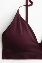 Soutien de diseño seamless, color bordó, con copas triangulares forradas, relleno extraíble y breteles finos ajustables. Presenta una banda elástica inferior ancha para mayor sujeción y un diseño sin aros ni cierres.