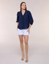 Blusa blanca de bambula con escote en V, pechera de encaje y mangas 3/4 abullonadas con detalles de puntilla.