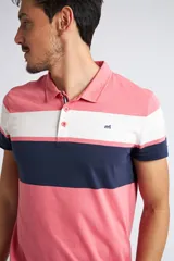 Remera polo de manga corta con diseño de franjas horizontales en colores rosado, blanco y azul marino. Cuenta con cuello clásico, cierre frontal de dos botones y logo pequeño estampado en el pecho.