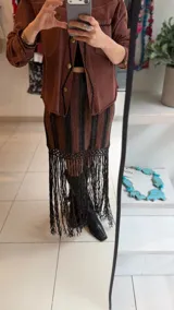 Falda tejida a rayas horizontales de corte irregular, con hilado de algodón y lúrex, y terminación de flecos tejidos a mano en crochet.