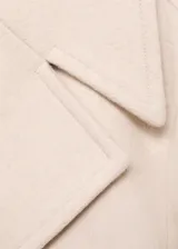 Abrigo corto de corte recto y diseño cruzado, confeccionado en tejido mezcla de lana. Presenta cuello con solapas de muesca, cierre frontal con botones oscuros y dos bolsillos laterales. Cuenta con forro interior y mangas largas.