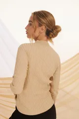 Buzo de tejido de punto color beige con lurex plateado, de cuello alto y mangas largas.