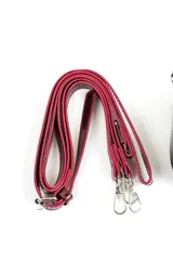 Cartera tipo bandolera de charol rojo, de diseño estructurado, con una hebilla metálica grande decorativa en el frente y correa larga ajustable y desmontable.