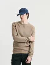 Sweater de punto con textura waffle, color negro, de corte clásico con cuello redondo y mangas largas con puños ajustados.