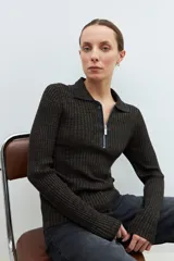 Sweater verde oliva de tejido de punto acanalado, con cuello polo, cierre metálico frontal y mangas largas.
