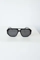 Lentes de sol con armazón de policarbonato negro y cristales tonalidad ámbar, con diseño de puente doble estilo aviador.