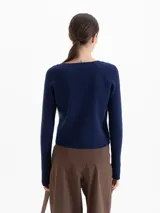 Cardigan de punto acanalado en color azul marino, con ajuste al cuerpo, mangas largas raglán y cierre frontal con botones dorados.