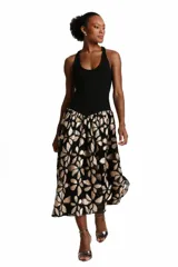 Vestido midi de Karech confeccionado en crepé negro en la parte superior y tul bordado con diseño floral en tonos dorados y beige en la falda. Presenta un diseño sin mangas con escote redondo y silueta definida.