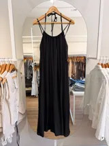 Vestido largo negro de silueta amplia y caída fluida, confeccionado en mezcla de modal y poliéster. Presenta escote fruncido con tiritas finas ajustables al cuello y espalda con elástico.