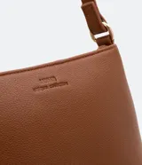 Bolso baguette pequeño color negro, con correa transversal ajustable y bolsillo interno con cremallera. Textura tipo saffiano y cierre por cremallera.