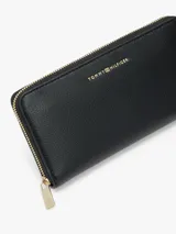 Billetera larga Tommy Hilfiger de diseño plano y textura granulada, con cierre perimetral y logo metalizado en el frente.