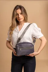 Bandolera de diseño moderno y funcional, confeccionada en nylon color marrón claro. Cuenta con múltiples compartimentos con cierre metálico, herrajes plateados y una correa ancha ajustable con detalle de marca.