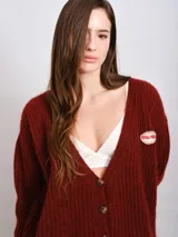 Cardigan marrón de punto grueso con cuello en V, cierre frontal con botones y parche bordado en el pecho.