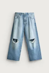 Jeans baggy fit de corte holgado en denim de algodón celeste, con tiro medio, cinco bolsillos, roturas en las rodillas y cierre frontal con cremallera y botón.