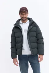 Campera puffer con capucha integrada, cierre frontal cubierto y bolsillos laterales. Confeccionada en nylon, presenta un diseño acolchado y funcional ideal para climas fríos.