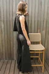 Chaleco negro de gamuza con cuello redondo y detalle de plumas en los hombros. Presenta un diseño sin mangas y corte recto, ideal para usar como top o prenda de superposición.