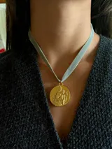 Collar tipo choker con cinta de terciopelo en color verde agua y dije circular chapado en oro 18k con relieve de la Virgen con el Niño.