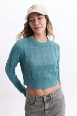 Sweater de punto color mostaza, con diseño de ochos y textura calada. Tiene cuello redondo, mangas largas y terminaciones acanaladas en puños y cintura.