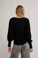 Top de tela con textura tipo gofrado, color negro, con escote redondo, botonadura henley y mangas largas abullonadas con puño.