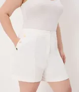 Bermuda de crepé color blanco, de corte holgado y tiro alto, con pliegues frontales y bolsillos laterales con detalle de botones. Confeccionada en poliéster y elastano.