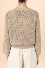 Sweater de punto color taupe, con cuello redondo, mangas largas abullonadas y puños ajustados. Presenta un tejido de punto grueso con textura.