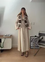 Chaleco sin mangas, confeccionado con cuadrados de cuero negro perforado combinados con cuadrados de crochet en hilo de algodón negro y blanco, con detalles centrales en rojo.