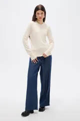 Sweater de lyocell al cuerpo, con cuello redondo a la base y mangas largas con detalle de botones en los puños.