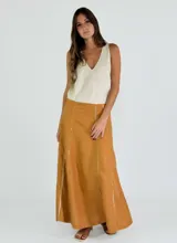 Pollera larga de lino color mostaza, con diseño de paneles verticales y costuras externas deshilachadas. Presenta tajos laterales y un calce fluido ideal para la temporada de verano.