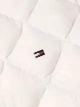 Chaleco acolchado color crema con relleno de plumón, cierre con botones a presión y logo bordado en el pecho.