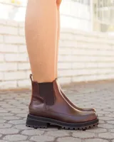 Botas tipo Chelsea de cuero color chocolate, con paneles elásticos laterales, suela track dentada y detalle de textura en el talón.