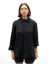 Camisa de lino de corte relajado, color negro, con cuello clásico, cierre frontal de botones y mangas largas con puños doblados.