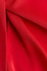 Vestido corto de color rojo, con escote redondo y detalle girado en el frente. Presenta mangas largas con abertura en los puños, falda con leve vuelo y cierre oculto en la espalda.