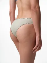 Bombacha tipo bikini de tiro medio confeccionada en algodón acanalado blanco, con bordes terminados en ribete con estampado animal print.