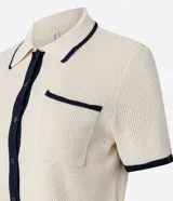 Blusa color crema con cuello inglés y detalles en azul marino, de punto más sostenible, en modelo comfort. Posee cuello inglés, manga corta, abotonado delantero, bolsillo y detalles contrastantes.