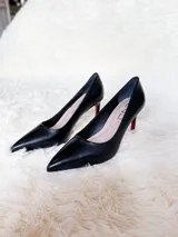 Zapatos de tacón alto con textura de reptil, color negro, con suela roja característica.